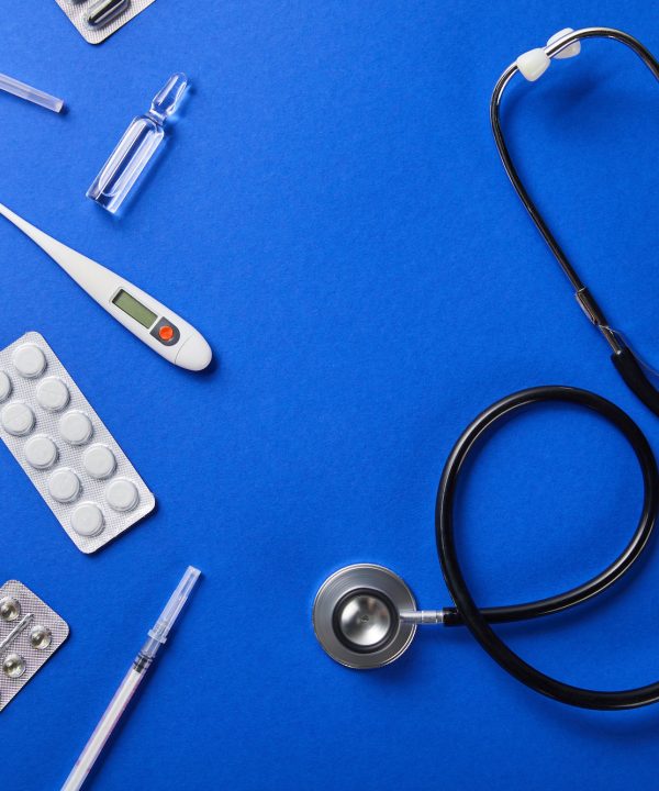 top view of stethoscope near various medical supplies on blue background